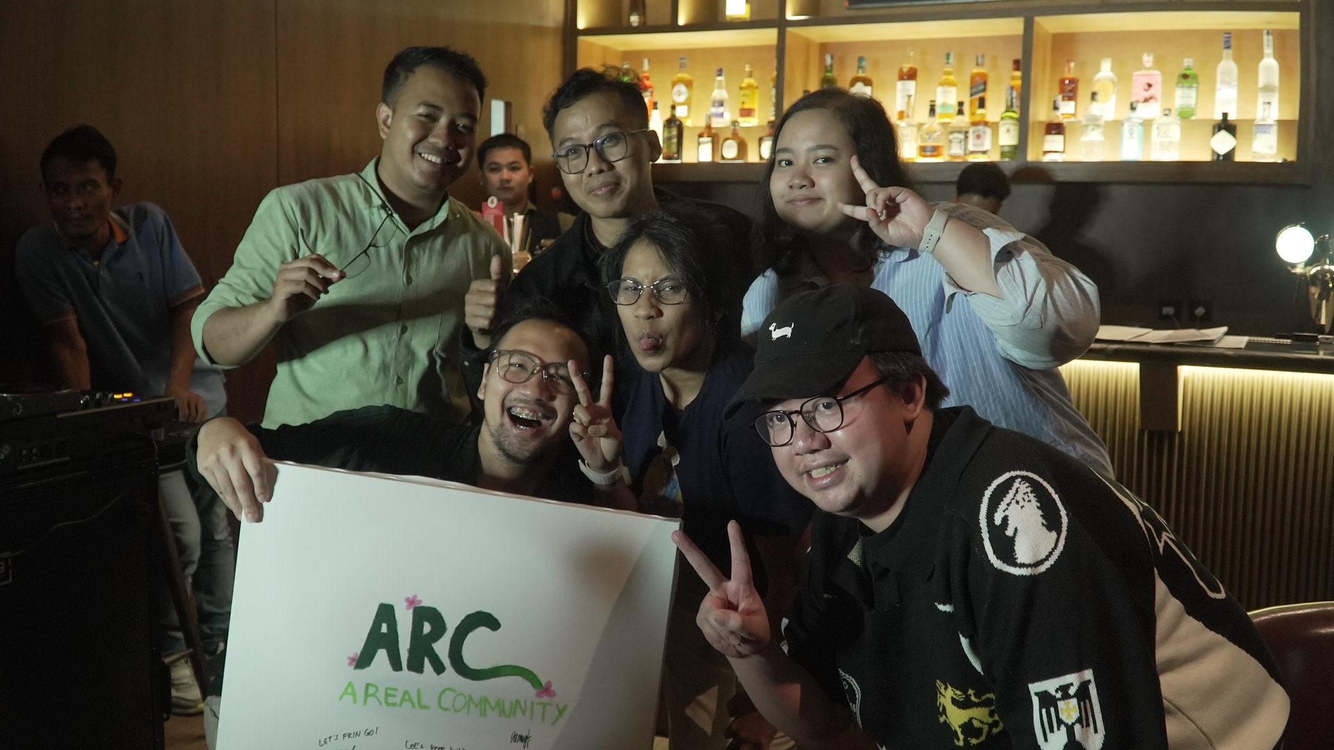 ARC community members posing with their signed banner at the bar