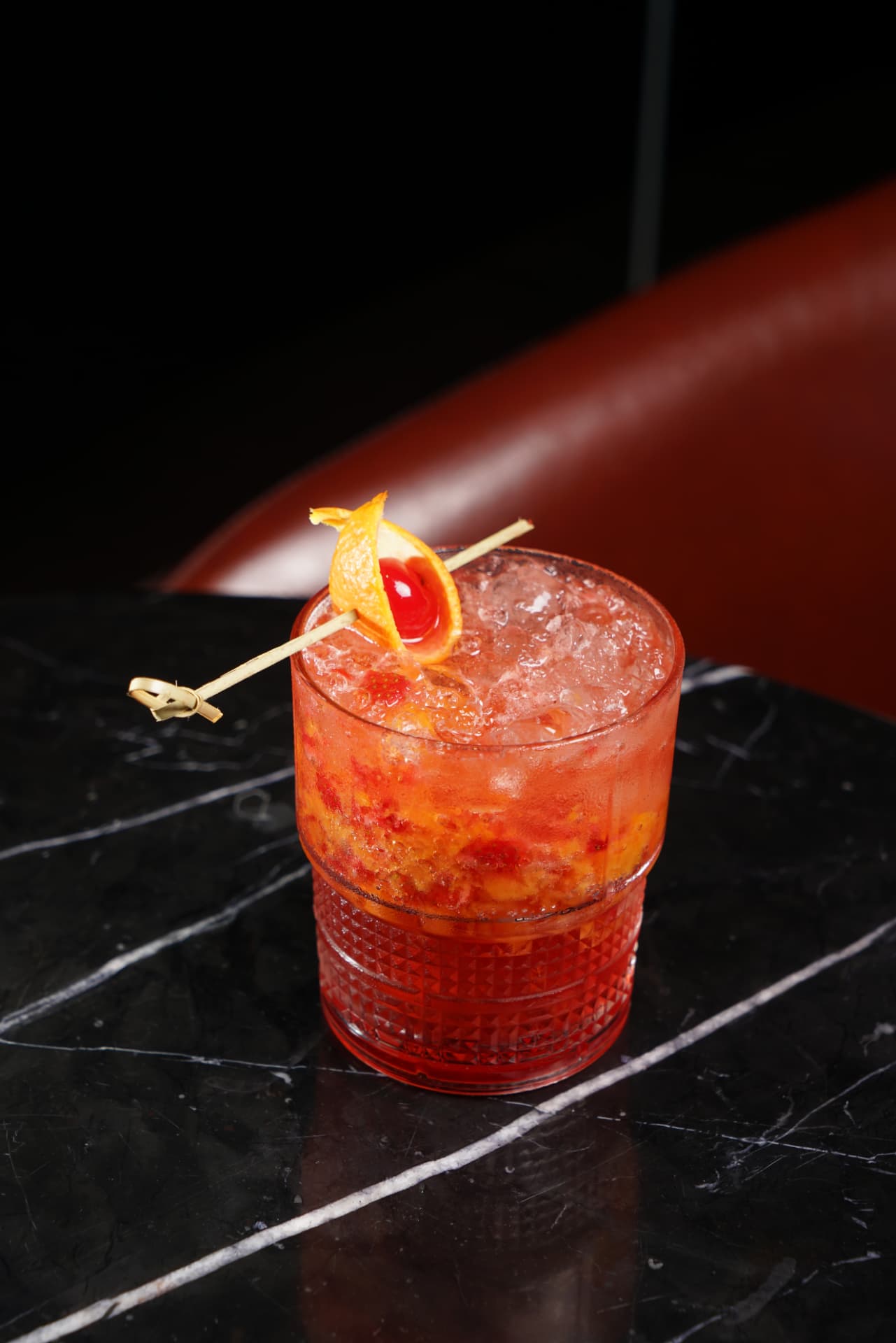 Red fruit cocktail on crushed ice with orange peel