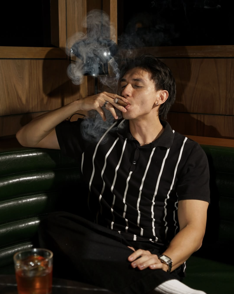 Guest enjoying a cigar in a leather booth at Le Baron Lounge
