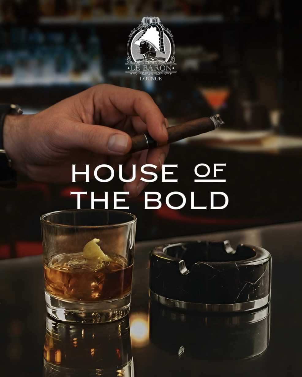 Cigar held above a whisky glass and ashtray at the bar